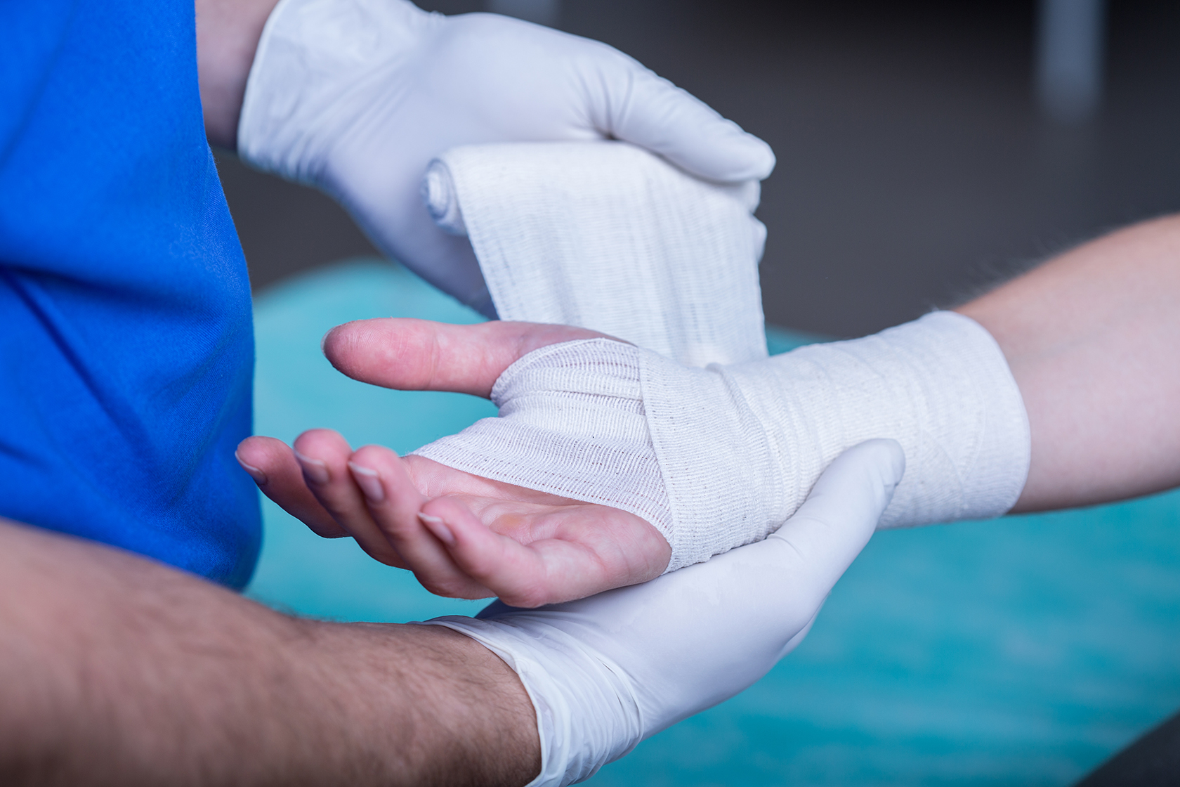 Close-up of male doctor bandaging a hand & wrist. 