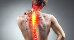 Stock photo of Young man holding his neck in pain. Spine highlighted
