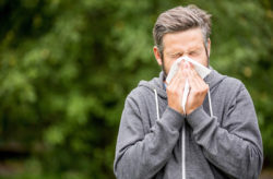 Allergies. Stock photo of a man sneezing outside