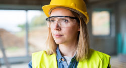 Stock photo of a woman construction worker wearing protective eye wear and a helmet